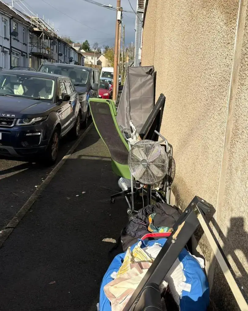 Office chair, fan and bags of bulky waste on a pavement awaiting collection