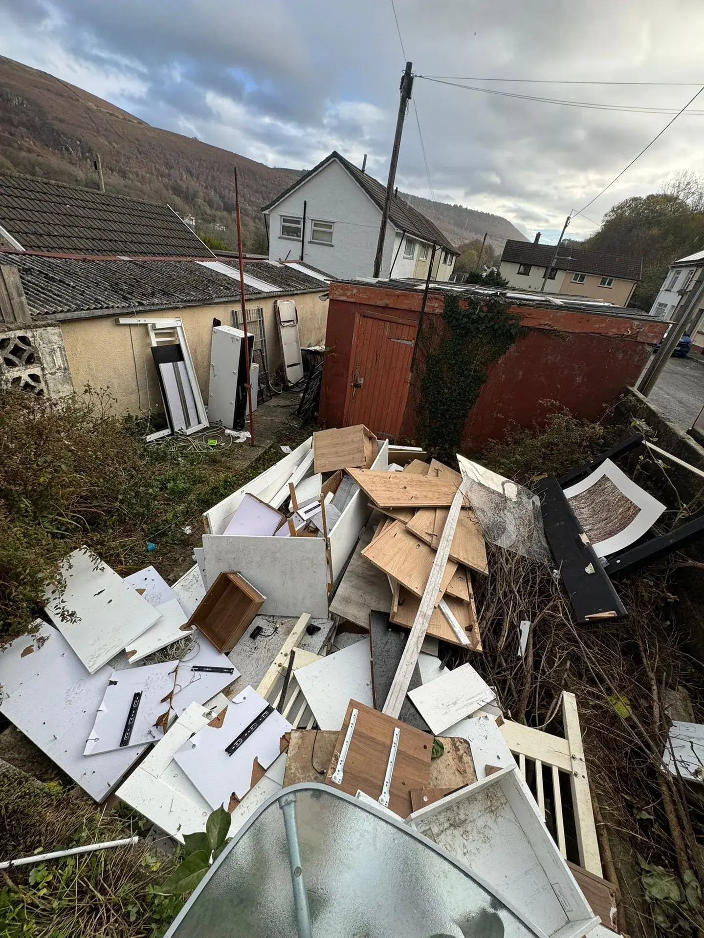 Garden full of broken furniture and rubbish before a garden clearance